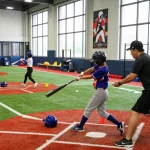 Young athletes training at hitclub baseball facility, practicing hitting techniques with coaches in action