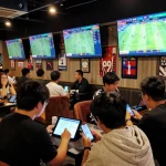 Players engage in sports betting strategies at nk88, analyzing live odds on multiple screens.